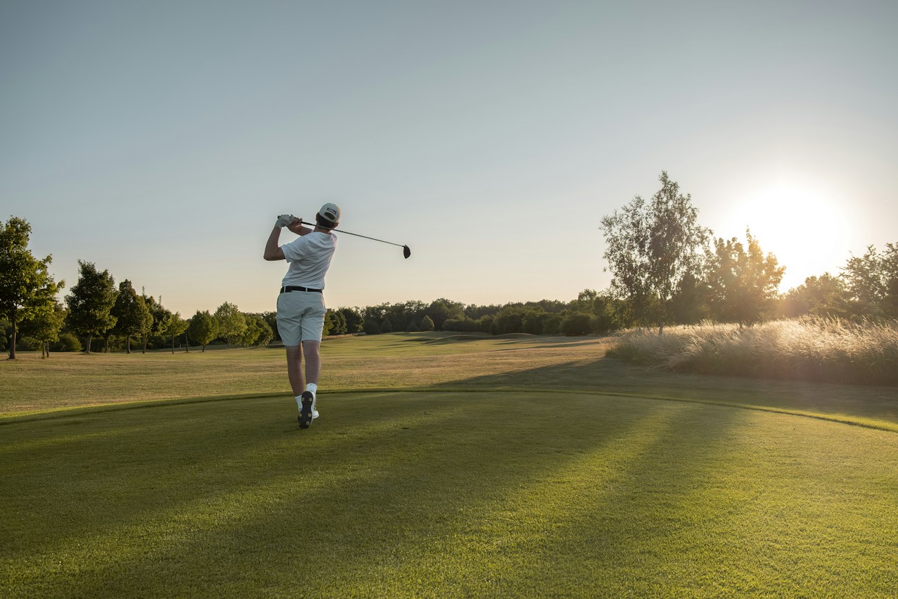 Golfer following through on a drive at sunset